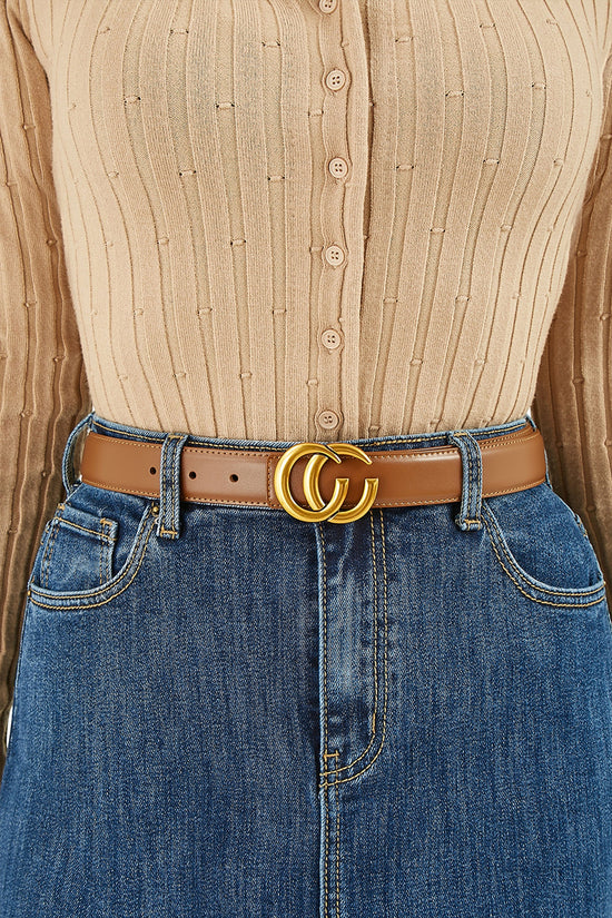 Close-up of a person wearing a beige button-up shirt and blue jeans with a brown belt featuring a gold buckle.