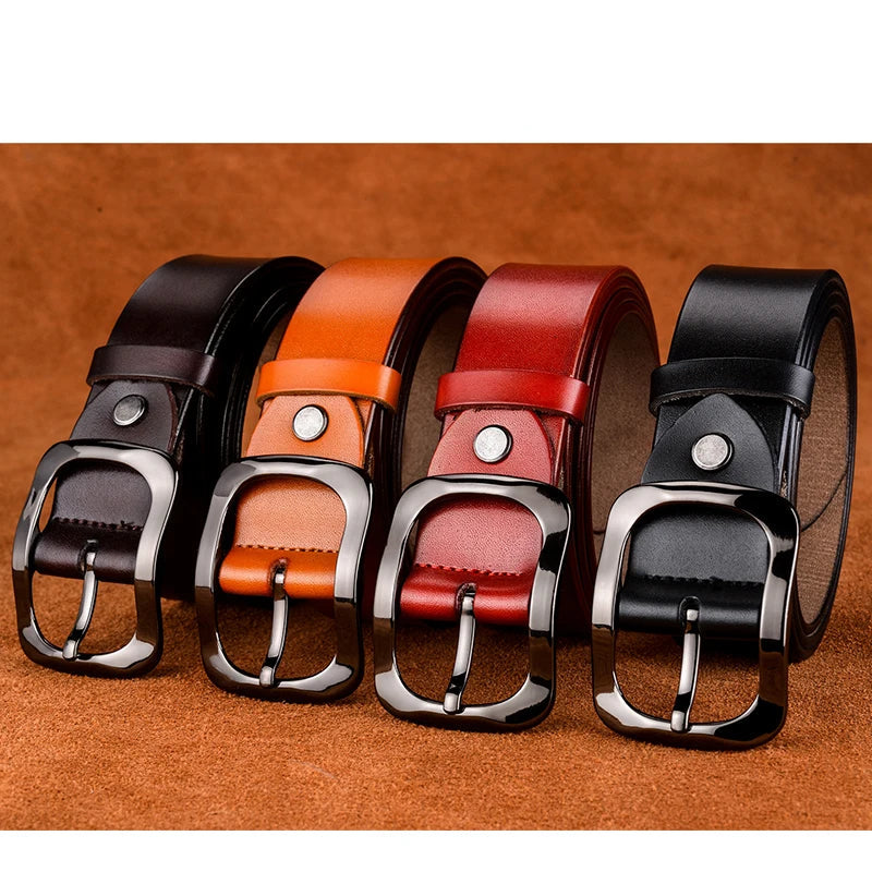 Four leather belts in black, brown, red, and black with silver buckles on a brown background.