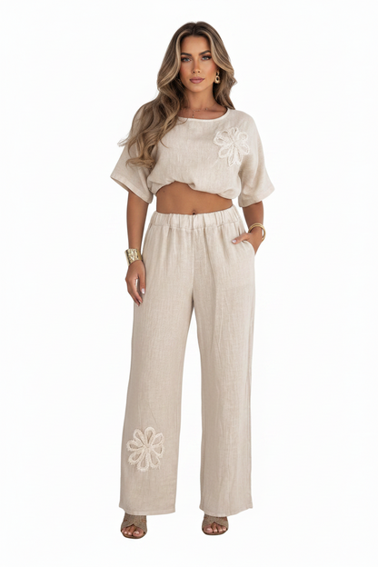 Woman wearing a beige outfit with floral embroidery on a white background