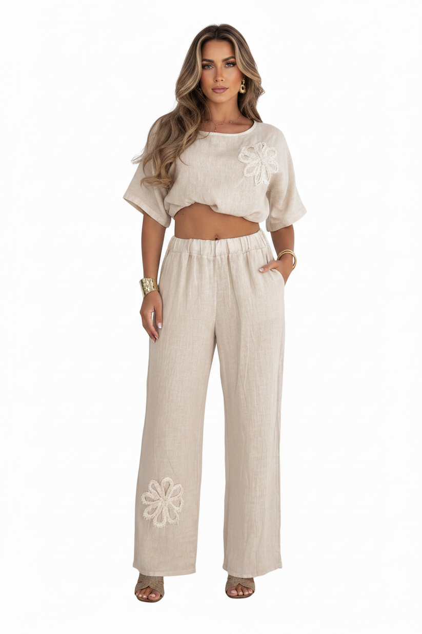 Woman wearing a beige outfit with floral embroidery on a white background
