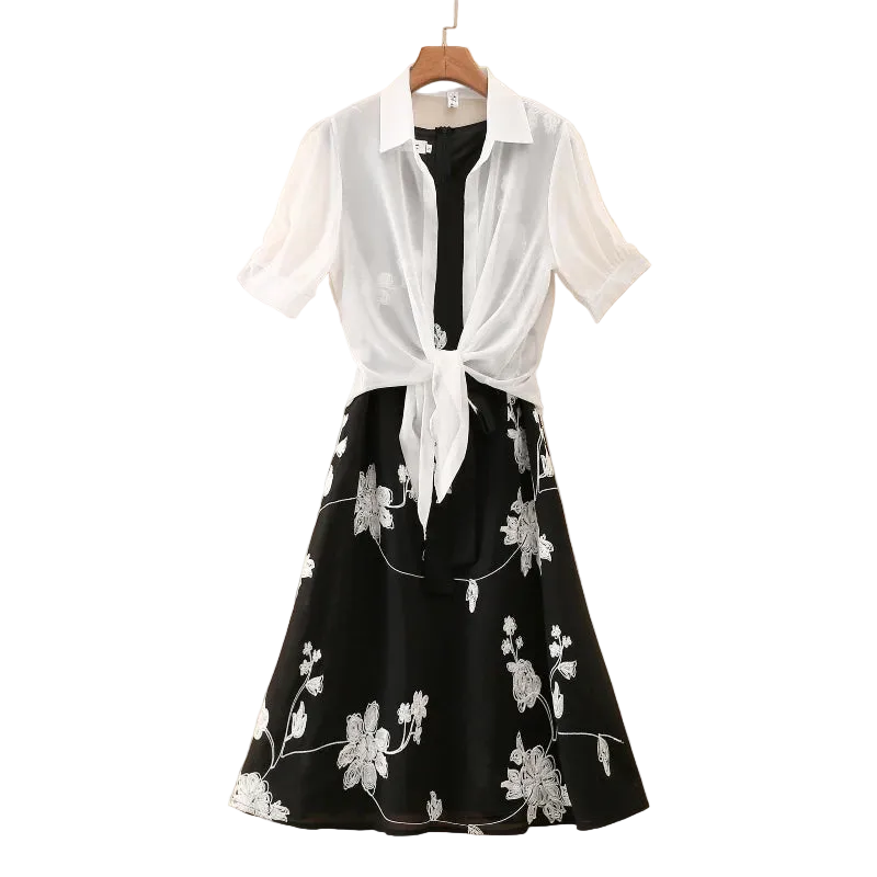 Black floral dress with a white shirt tied around the waist on a beige background