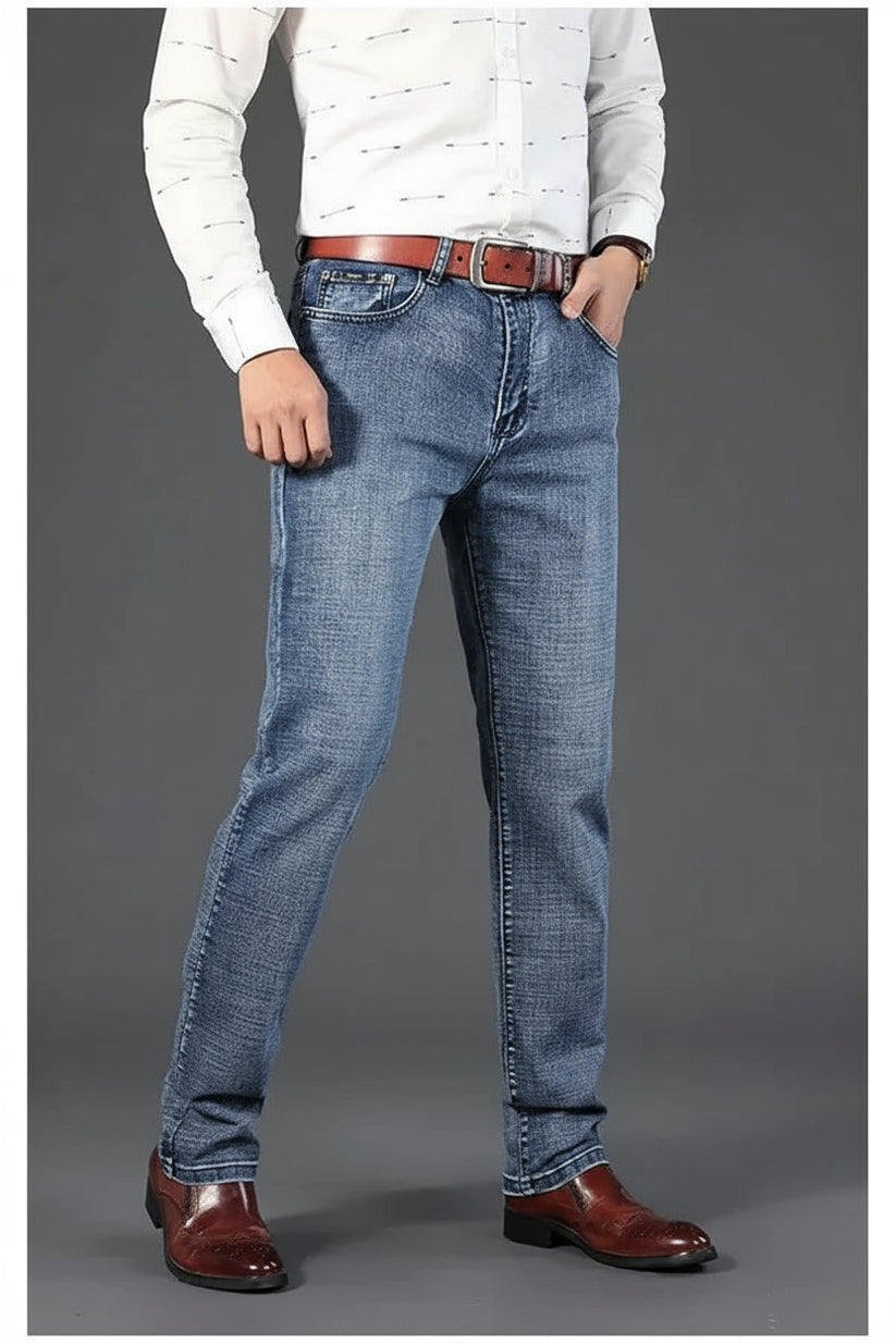 Person wearing blue jeans and brown shoes on a gray background
