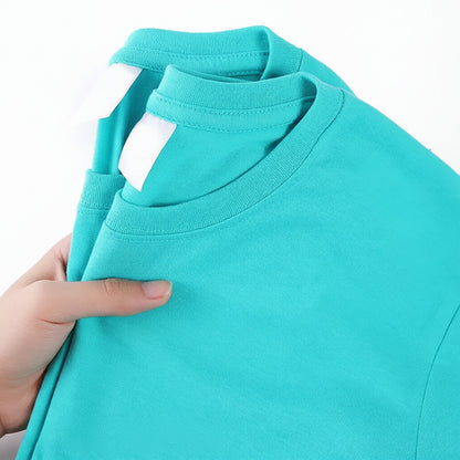 Turquoise t-shirt held by a hand with a visible label on a white background