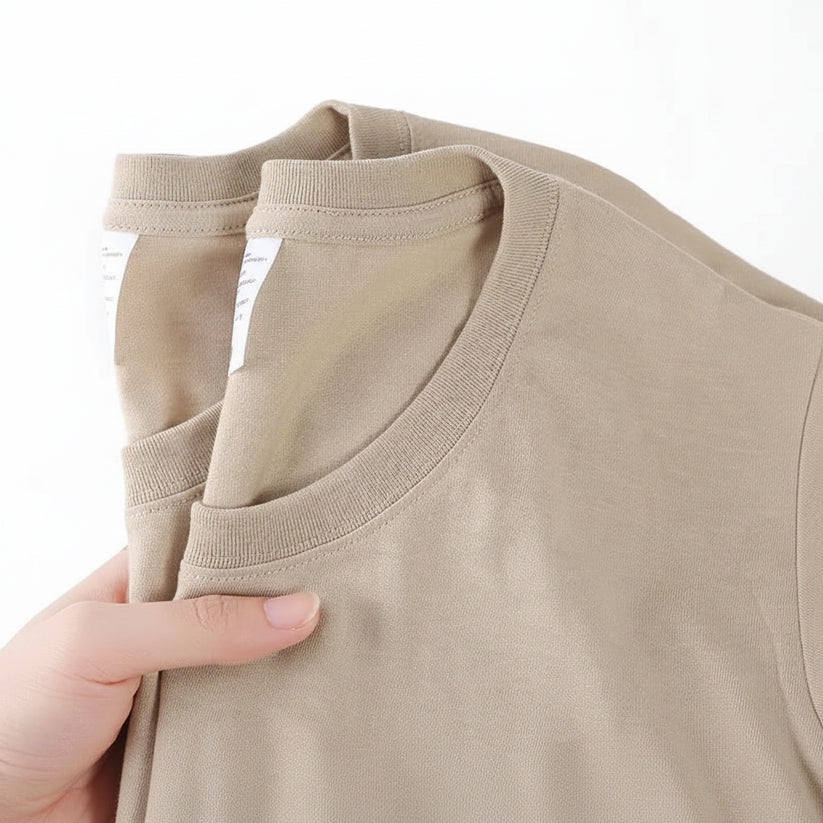 Close-up of beige fabric with a hand holding it, featuring text '100% Cotton' on a white background.