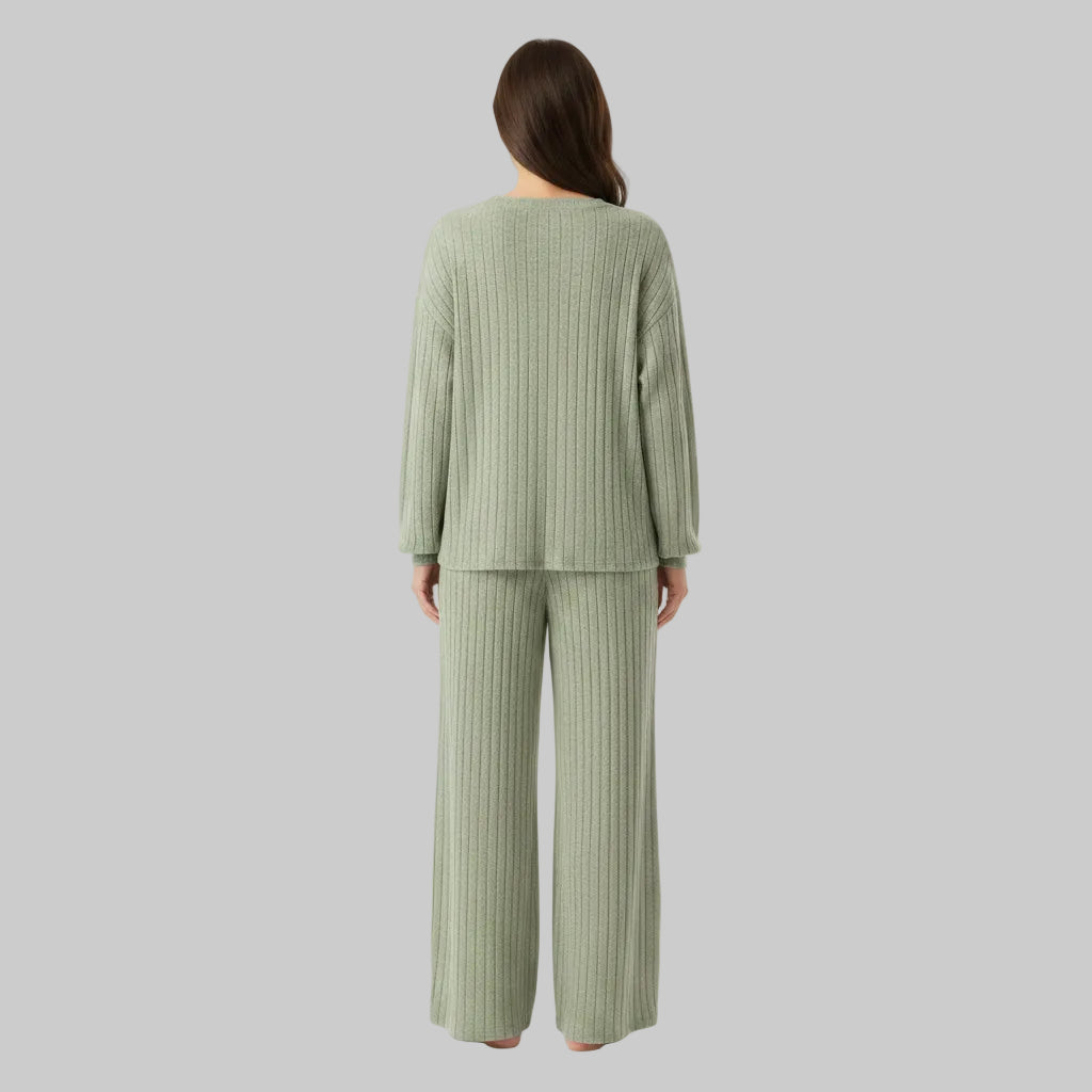 Person wearing a ribbed knit suit in a room with decorative elements.