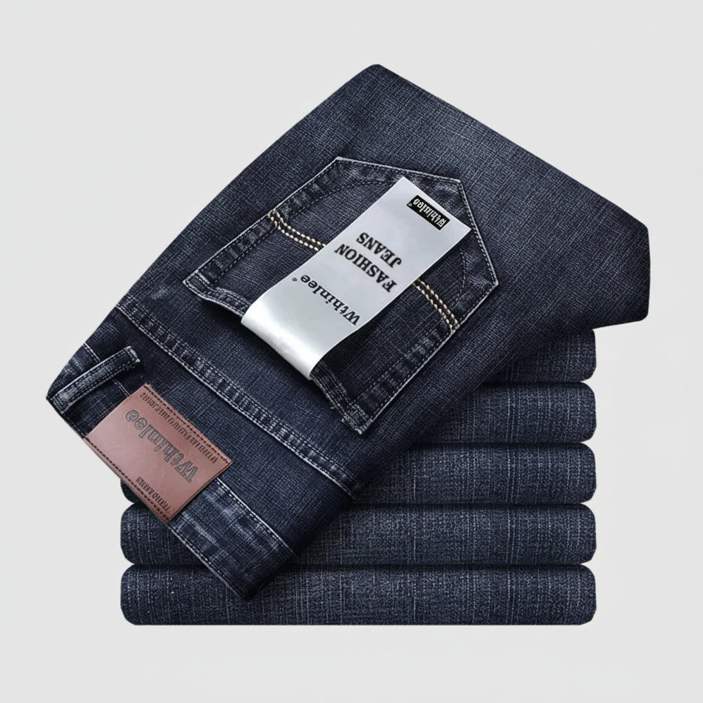 Stack of folded dark blue jeans with a visible brand tag on a light gray background