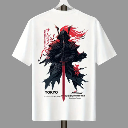 White short-sleeve T-shirt hanging on a hanger against a plain light gray wall, featuring a large back graphic of a black samurai warrior with red hair and sword, plus red Japanese text and small black text near the hem.
