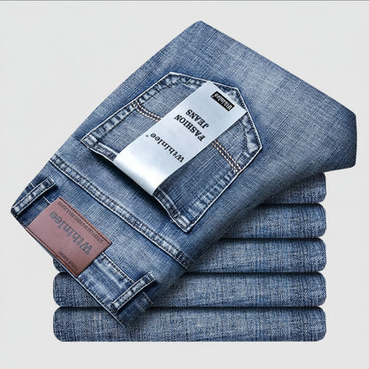 Stack of folded blue jeans with visible brand labels on a light gray background
