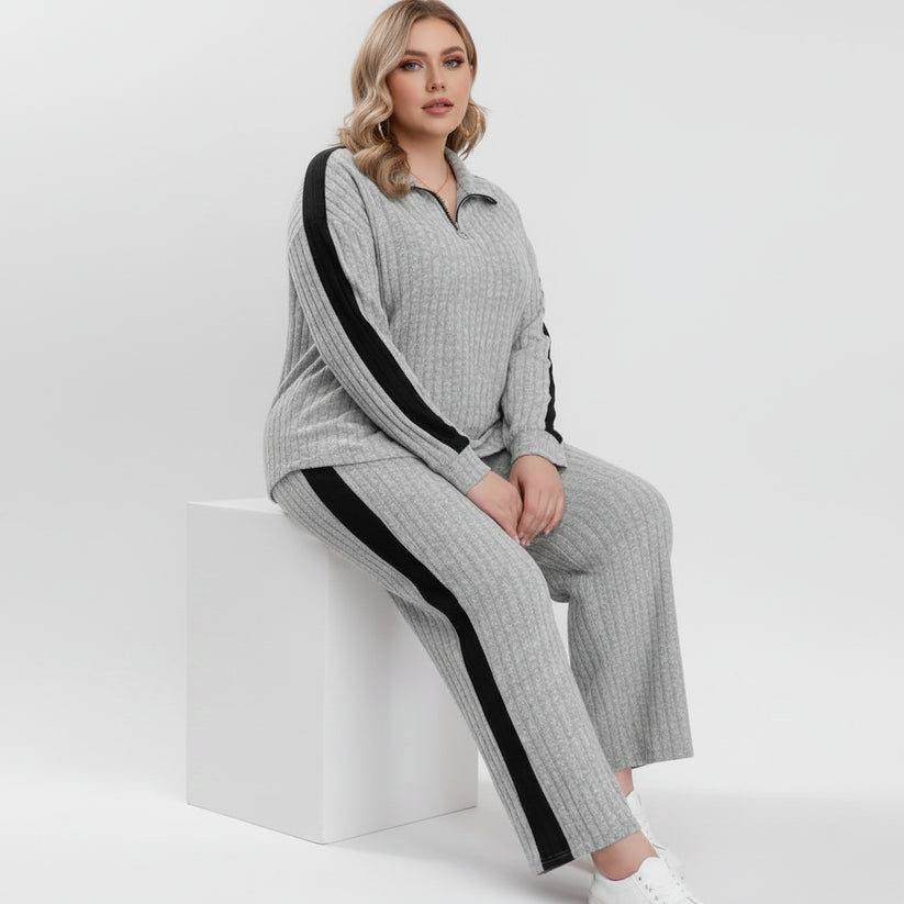 Person wearing a gray lounge set with black stripes, sitting on a white chair.