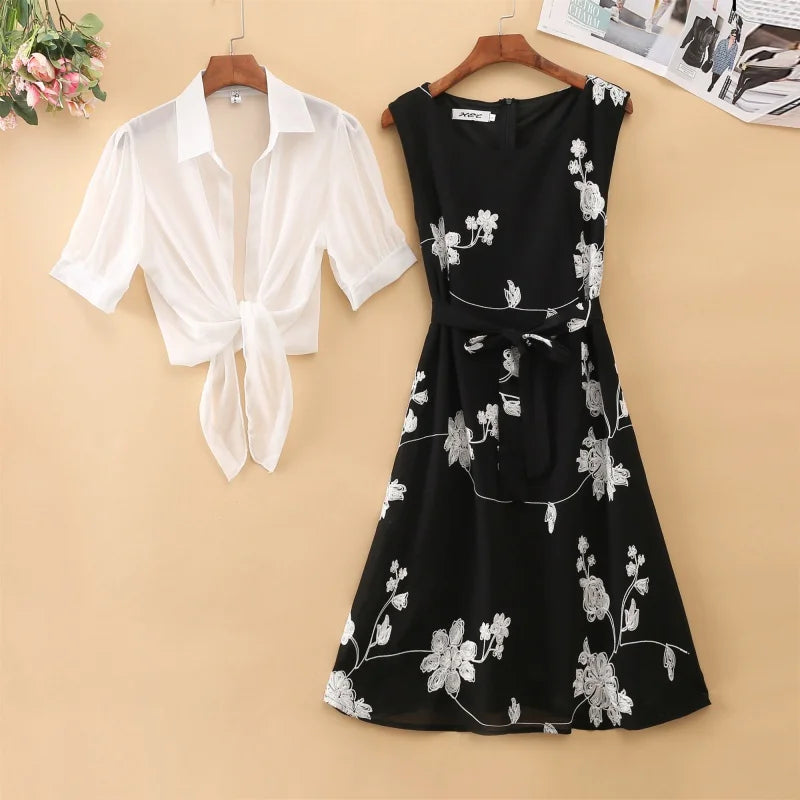 White shirt and black floral dress on hangers against a beige wall.