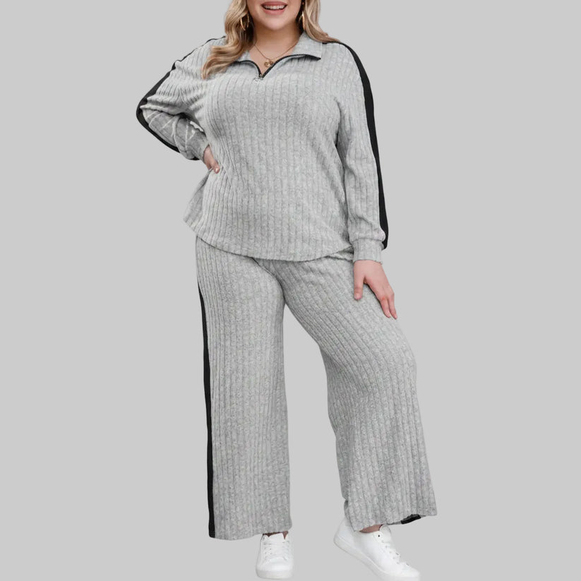 Woman wearing a gray ribbed lounge set with black trim on a white background