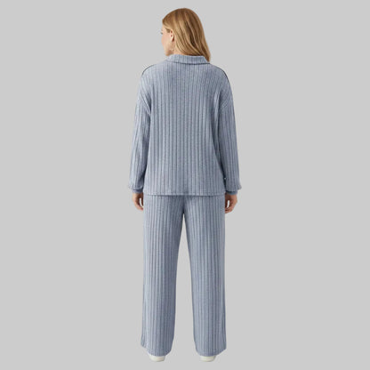 Person wearing a blue ribbed pajama set in a room with white walls and wooden floor.