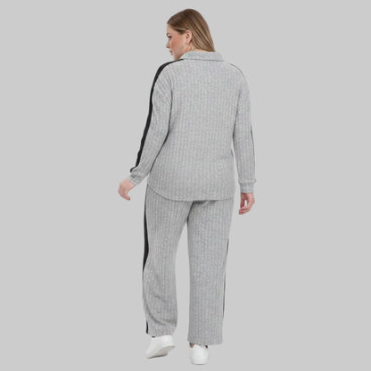 Person wearing a gray checkered outfit with white sneakers on a plain background