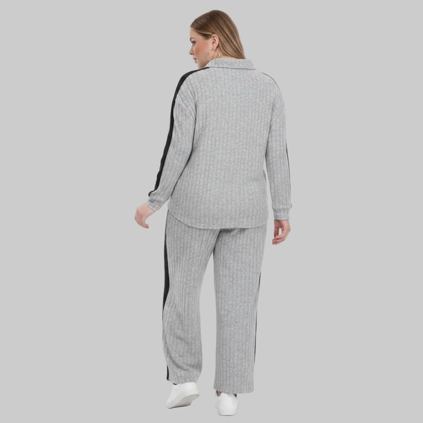 Person wearing a gray checkered outfit with white sneakers on a plain background