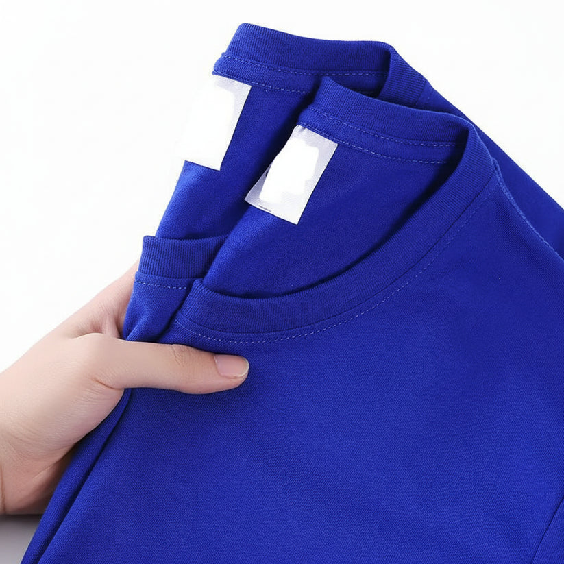 Blue t-shirt held by a hand with a visible tag, on a white background