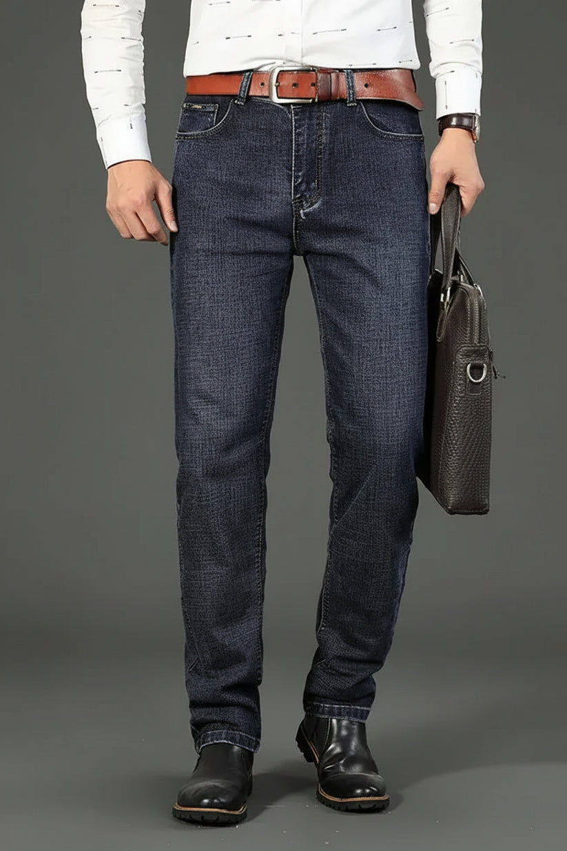 Person wearing dark blue jeans and holding a brown leather briefcase on a gray background