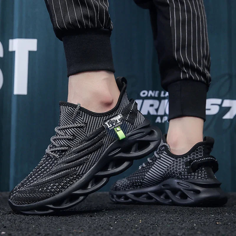 Black athletic shoes with a unique sole design worn by a person against a blurred background.