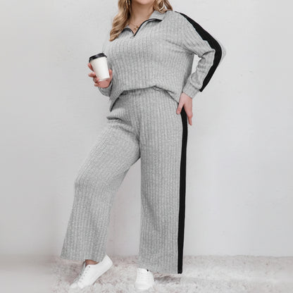 Woman wearing a gray knit outfit with black side panels, holding a coffee cup.