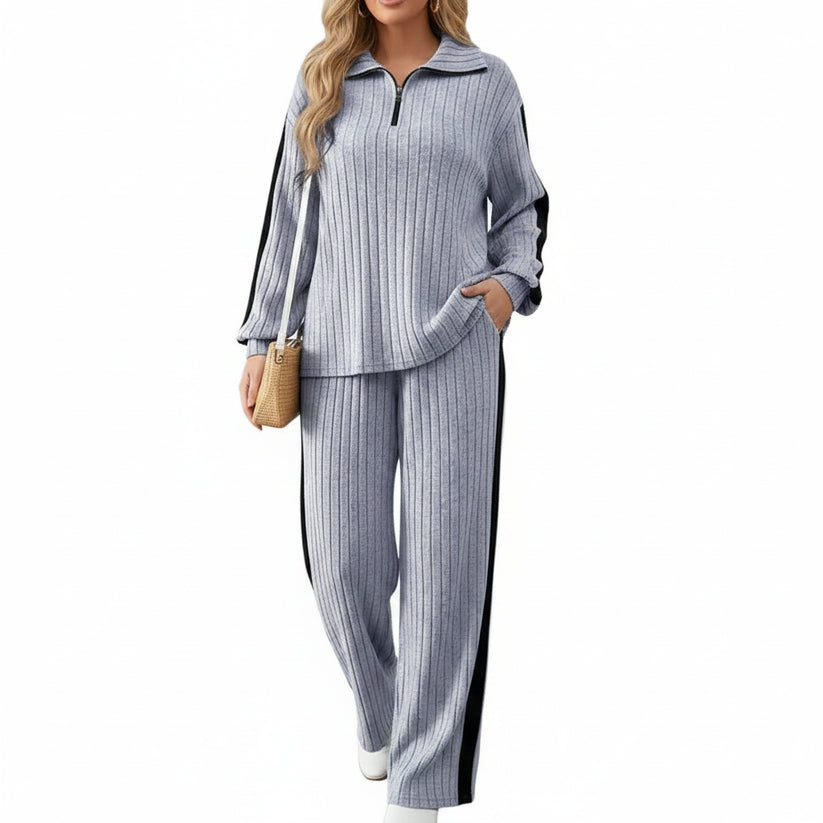 Person wearing a gray ribbed outfit with a wooden door and plant in the background