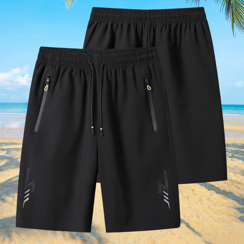 Black shorts with zippers on a beach background, featuring the brand 'MANTLCONX'.