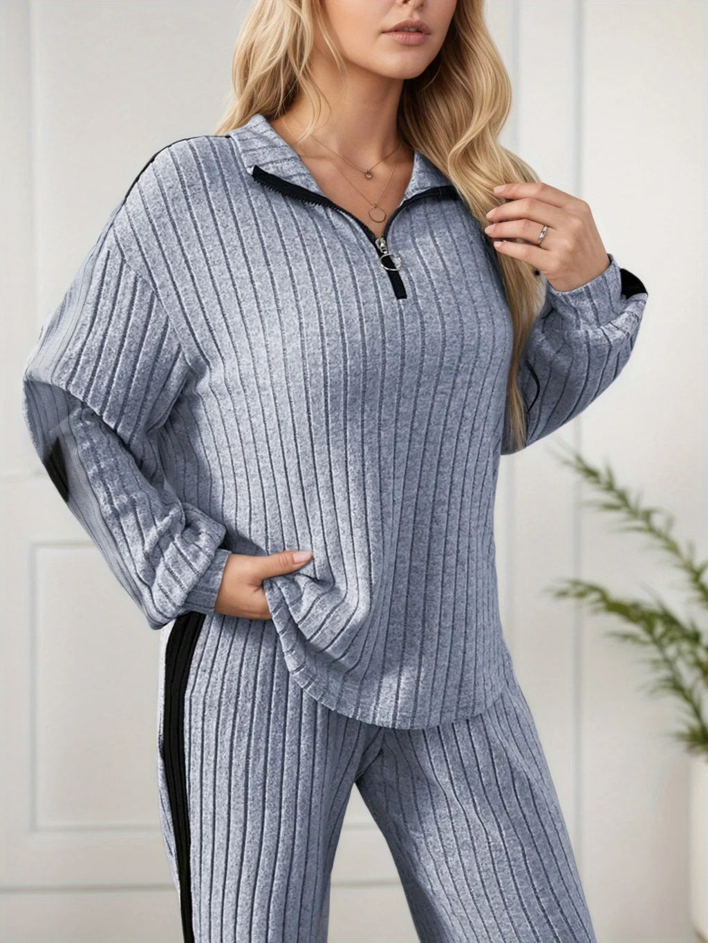 Woman wearing a ribbed gray tracksuit against a white background