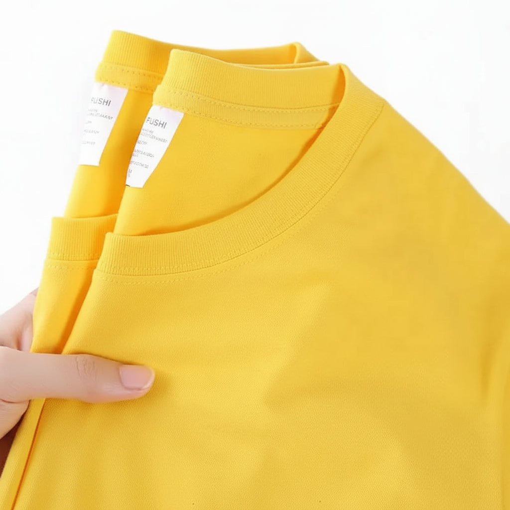 Yellow t-shirt with a brand label held by a hand on a white background